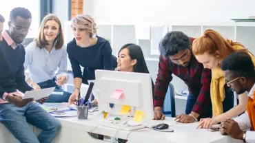 A group of people in an office setting collaborating on a project.